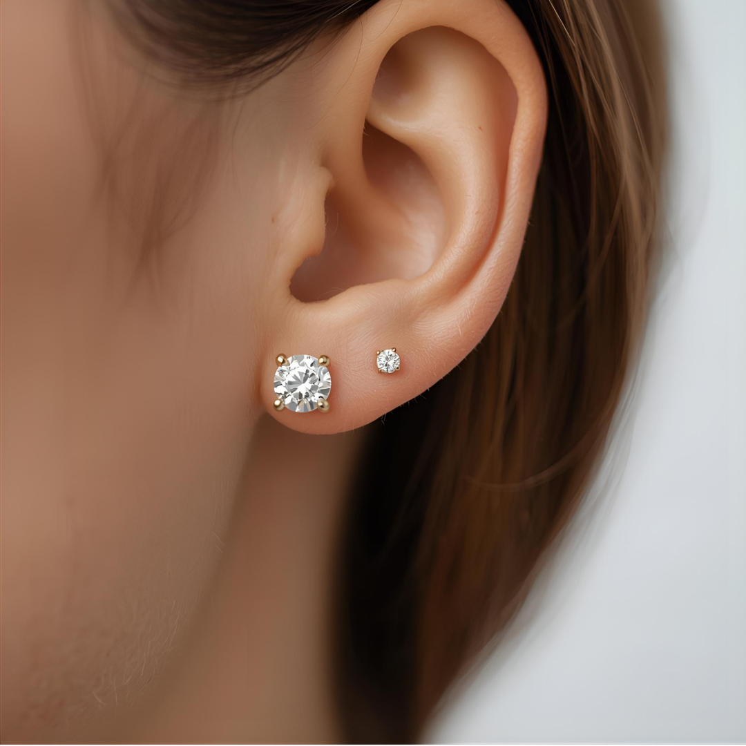 Close-up of an ear wearing two lab created diamond stud earrings on a neutral background
